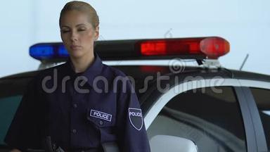 漂亮的女警察站在警车旁边看着摄像机，<strong>值班</strong>